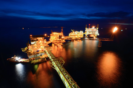 The supply boat is working at large offshore oil rig at night with twilight backgroundの写真素材