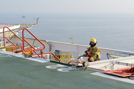 fireman is guarding for offshore helicopter before start up engine at oil rig platformの写真素材
