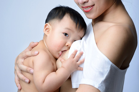 Young asian mother holding her baby and breast feeding babyの写真素材