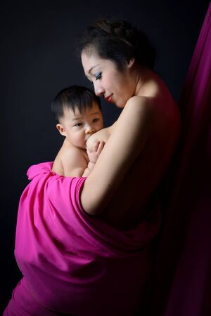 asian mother holding and breast feeding her babyの写真素材