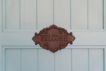 Brown Wooden Vintage Sign with the word "welcome"  on the blue wooden doorの写真素材