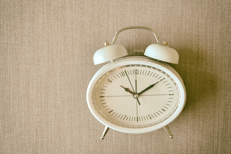 Retro alarm clock on a bed Photo in retro color image style