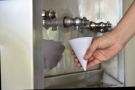 Man getting a cold, refreshing drink from the water cooler.の写真素材