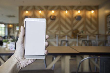 Hand holding Blank Screen of Smart phone with blurred sitting on cafe backgroundの写真素材