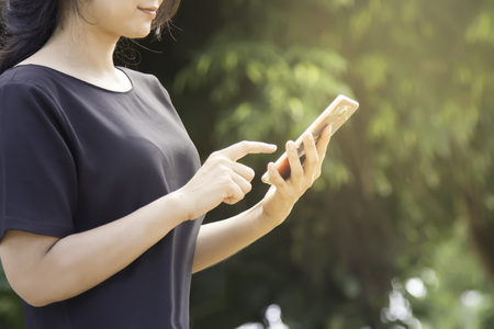 Woman typing text message on smart phone.Young woman outdoors on cell phone.の写真素材