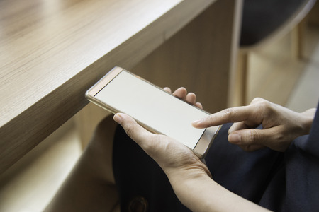 Closeup woman hand typing on smart phone.girl using smart phone in cafe. hand holding smart phone white screen vintage toneの写真素材
