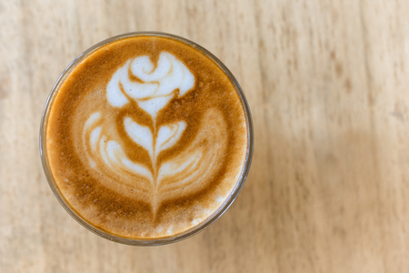 A cup of coffee with latte art rose flower pattern in a white coffee cup on wooden table in coffee shopの写真素材