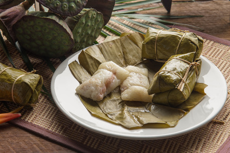 khao tom mad Thai food style dessert, made from banana and glutinous rice, wrap with banana leaf on wooden tableの写真素材