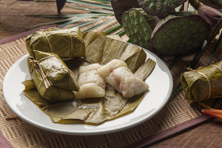 khao tom mad Thai food style dessert, made from banana and glutinous rice, wrap with banana leaf on wooden tableの写真素材
