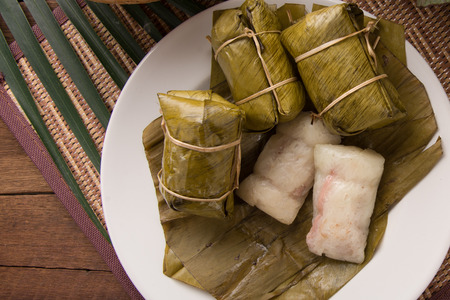 khao tom mad Thai food style dessert, made from banana and glutinous rice, wrap with banana leaf on wooden tableの写真素材