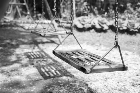 Empty swings on playground.wings in city park. Empty chain swings in summer kids children playground.の写真素材