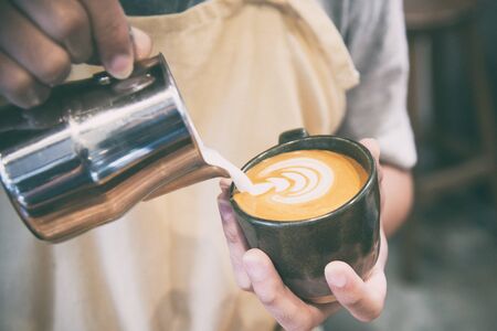 hand of barista making latte or cappuccino coffee pouring milk making latte artの写真素材