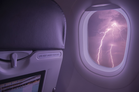 Ligthning storm viewed from inside an airplane windows.Airplane flight during a thunderstorm and rain, bad weatherの写真素材
