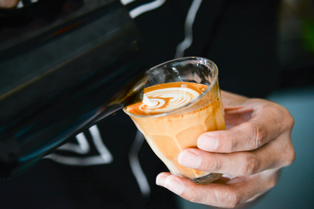 Barista making latte art focus in milk and coffee.hand of barista pouring milk making latte artの写真素材
