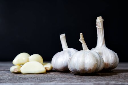 Garlic Cloves and Garlic Bulb. sliced garlic, group of garlic on wooden table black backgroundの写真素材