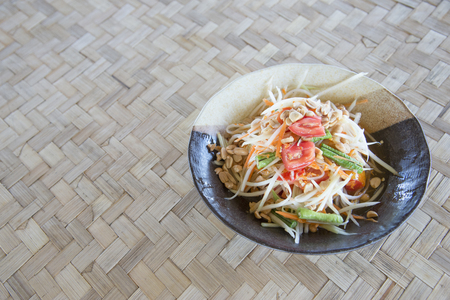Thai food background.papaya salad som tam topview famous traditional thai food made from papaya,chili,tomato and peanut on bamboo texture backgroundの写真素材
