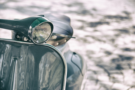 Vintage film style motorcycle headlight. Close up detail of elegantly designed vintage scooter parked in a street の写真素材