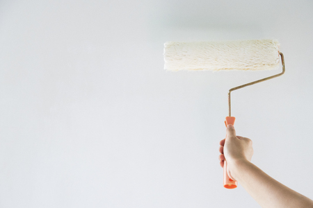 painter arm painting a wall with paint rollerの写真素材