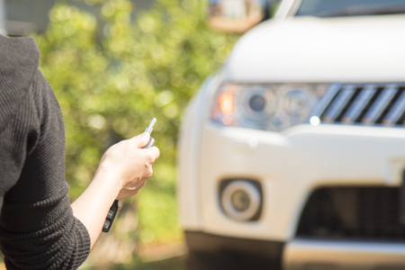 woman hand holding the remote control to lock the car door.car security anti thief alarm systemの写真素材