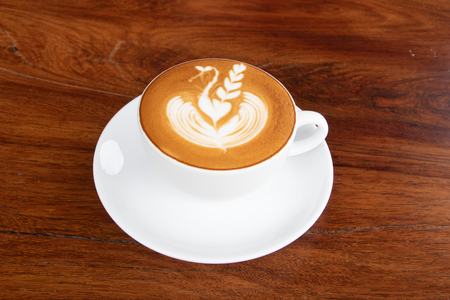 coffee cup latte art on wooden table.hot drink coffee with milk froth for breakfast.heart shape art foam texture top view.の写真素材