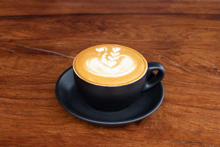 coffee cup latte art on wooden table.hot drink coffee with milk froth for breakfast.heart shape art foam texture top view.の写真素材