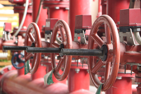 Red valves on metal pipe. Valve is a device that regulates, directs or controls the flow of a fluid...