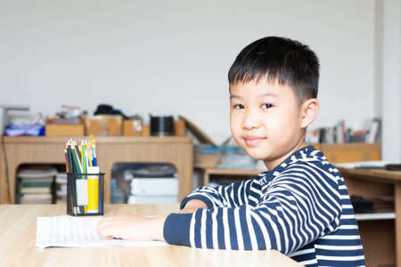 Asian boy who are studying in elementary school reading and doing homework by himself at home.の写真素材