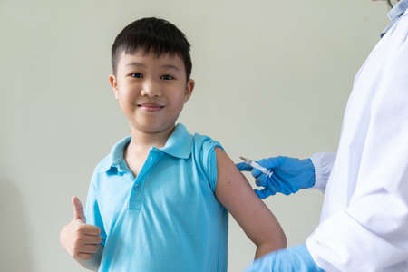 The doctor is using a syringe to vaccinate the Asian child's shoulder in hospital. Virus protection with vaccination concept.の写真素材