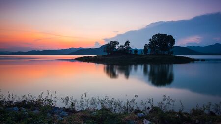 Small island at reservoir of dam after sunsetの写真素材