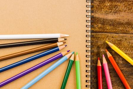 Gray notebook with colorful pencils on the wooden tableの写真素材