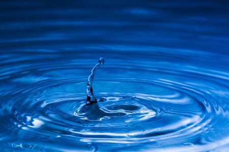 Water splash in dark blue color with a drop of waterの写真素材