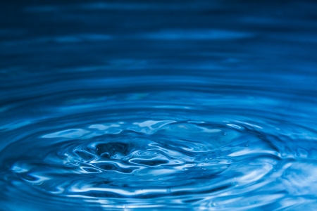 Water splash in dark blue color with a drop of waterの写真素材