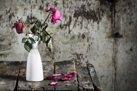 Withered roses in vase on old woodenの写真素材