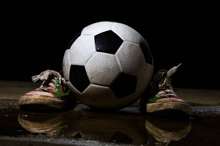 Dirty sneakers with soccer ball on black backgroundの写真素材