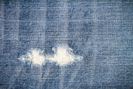 Texture of blue torn denim jean with hole and threads, backgroundの写真素材