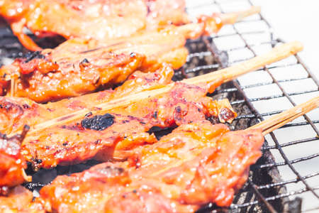 Close up of Grilled chicken stick on the flaming grill, Thai traditional cookingの写真素材