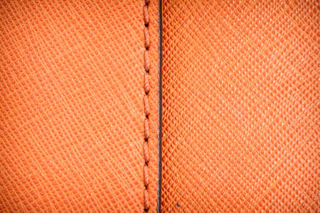 Orange textured leather background with stitchの写真素材