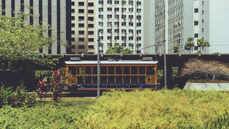 Old-fashioned yellow bonde tram tourist in Rio de Janeiro with residential houses behind, Santa Teresa, sunny summer day, Brazilの写真素材