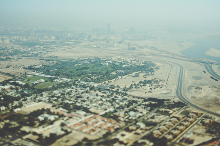 True tilt shift shooting from top of Dubai: residential buildings, park, sand areas, highways and river, sunny summer day with hazeの写真素材