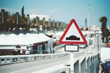 Close-up view of triangular speed bump road sign with blank place for additional information, near sloping road on sunny and bright summer day, Barcelona, Spainの写真素材