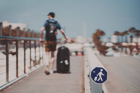 Blurred silhouette of a man with huge luggage bag going over narrow special pathway on sunny summer day with clear sky in Barcelona, special Icon means path for people with luggageの写真素材