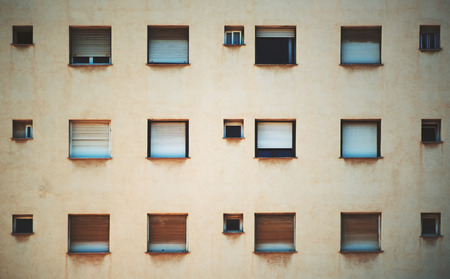 Beige facade of residential building in Barcelona with regular pattern of windows of different size,...