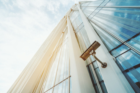 Single surveillance camera on facade of contemporary business skyscraper on sunny summer day, security camera on metal beam of modern office building with copy space for young advertising text messageの写真素材