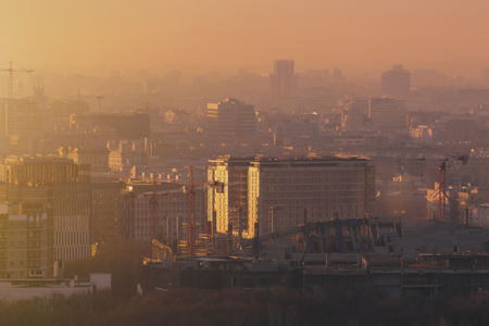 Close-up shooting from top of morning metropolitan city: huge stadium under construction with cranes and beams, residential buildings and districts, multiple facades, hazy horizon, Moscow, Russiaの写真素材