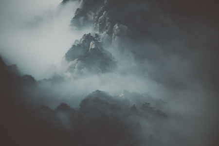 True tilt-shift scenery view of magical misty mountains in cold morning light surrounded by low...