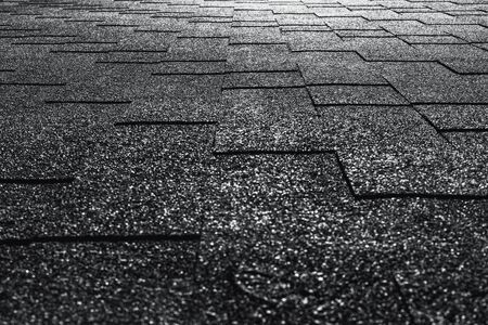 Side view of soft roof tiled black and white grainy texture on the top of summer house illuminated by sunの写真素材