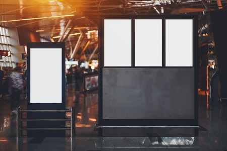 Blank four electronic departures and arrival informational billboards with clean space for publicity content or messages, narrow advertising mock-up placeholders in interior in airport terminal hallの写真素材
