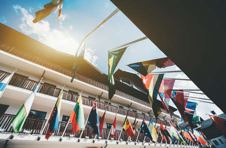 Wide-angle view of buildings facades with multiple national flags of different countries fixed to them regularly, sunny day, Estosadok district, Sochi, Russiaの写真素材