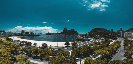Panoramic view from a high point: Rio de Janeiro urban landscape in the Botafogo district with the bay and two highways in foreground; Sugarloaf mountain with its ropeway in the background; bright dayの写真素材