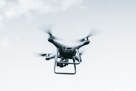 UAV quadcopter with an underslung digital camera is filming an online broadcast; the white flying...